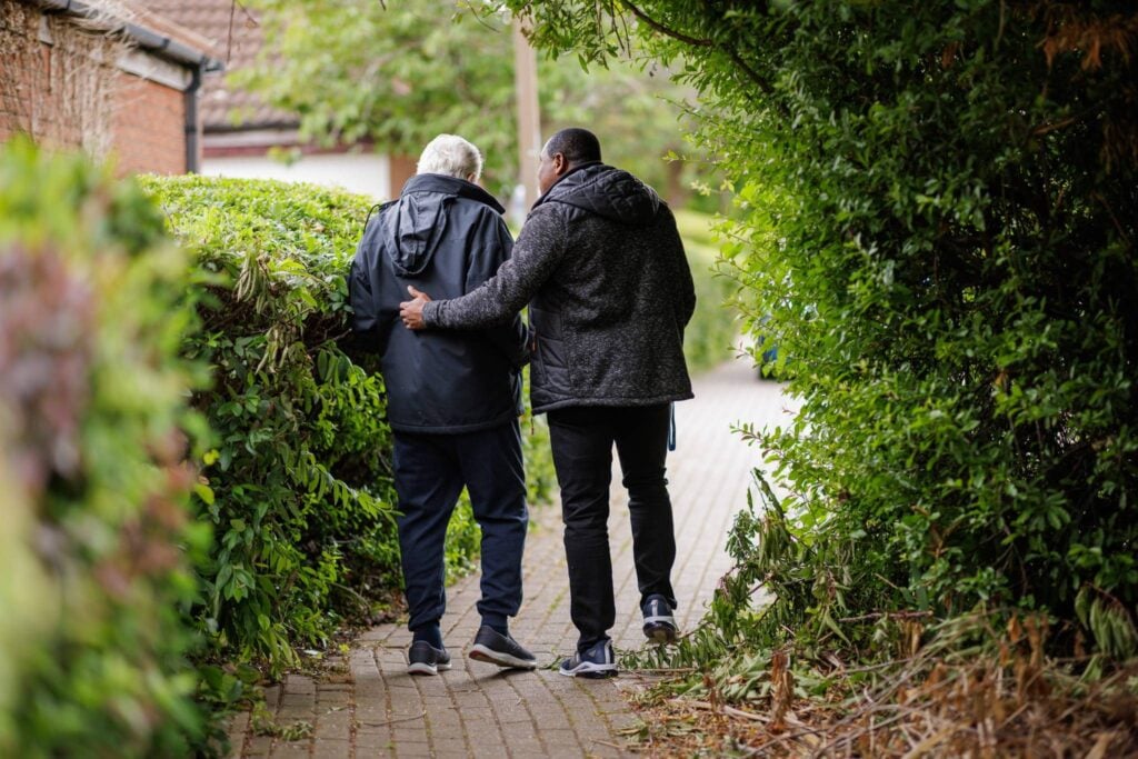 Two people walking, down a leafy path