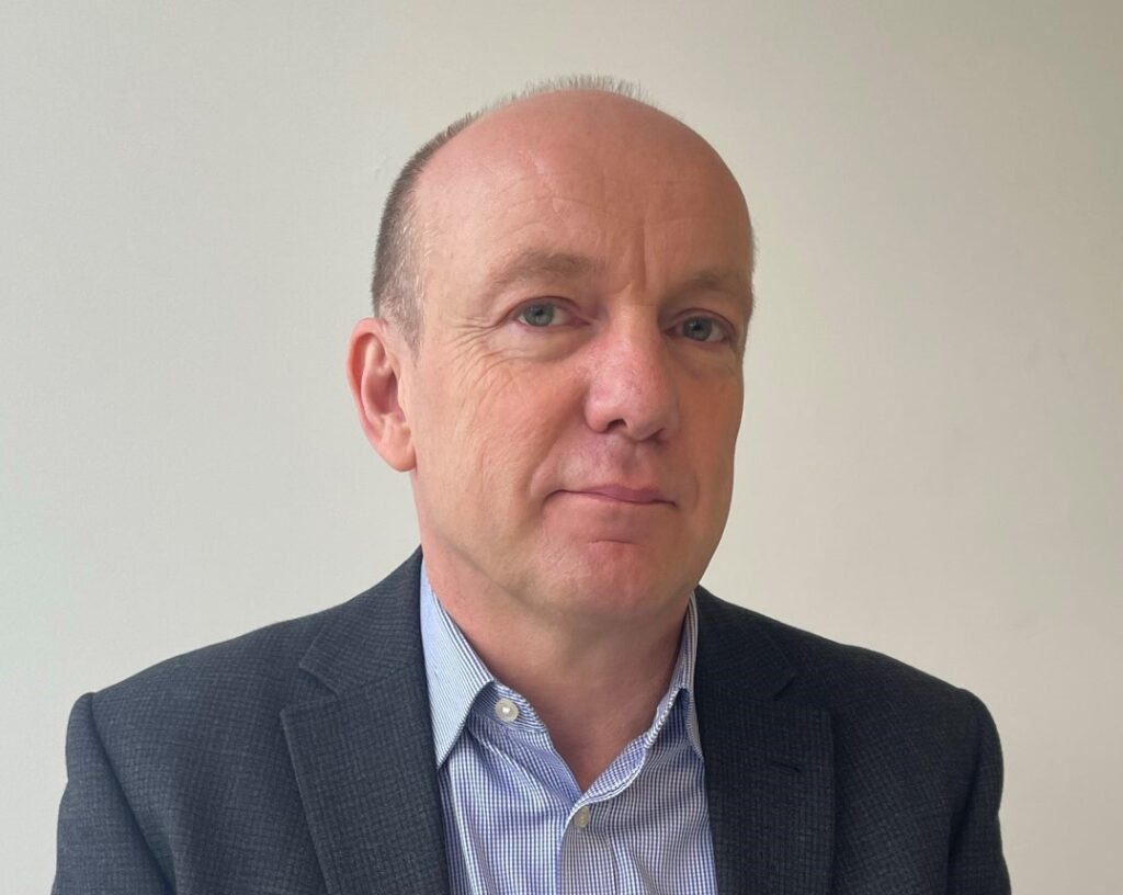 Headshot image of trustee Neil Churchill in a grey suit