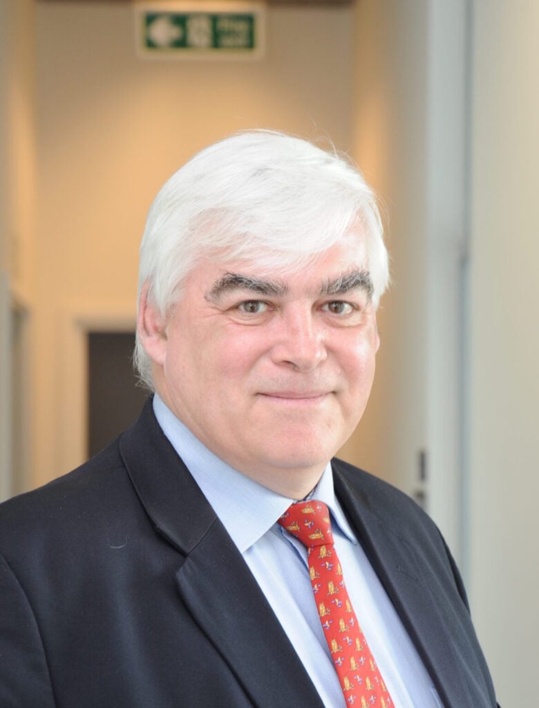 Headshot image of Brainkind Trustee, Nigel Scott, wearing a dark suit and red tie.